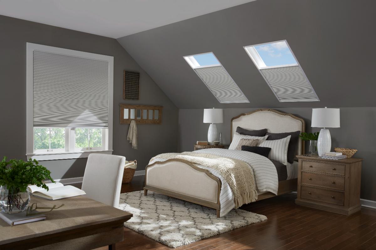 A comfortable bedroom under a slanted gable room has roller sades on the skylights - vu window treatments, FL