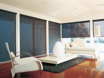 Motorized roller shades lowered across a wall of windows