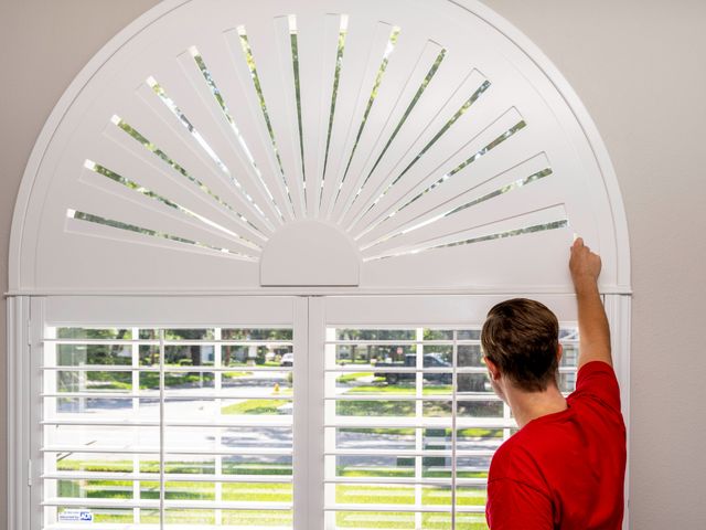 A VU installer fitting an arched shutter to its opening