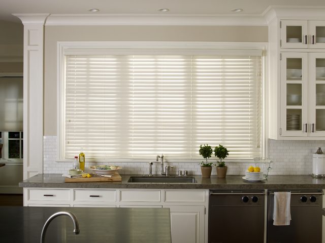 White faux wood blinds above a kitchen sink