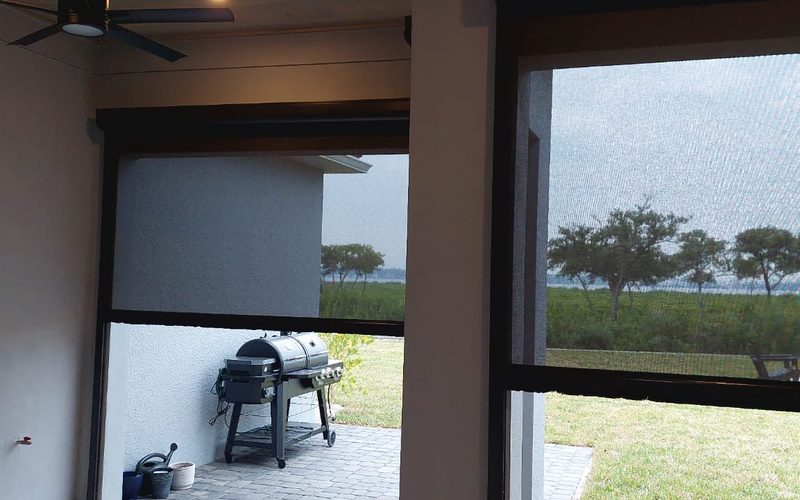 Motorized outdoor screen lowered across a Florida lanai